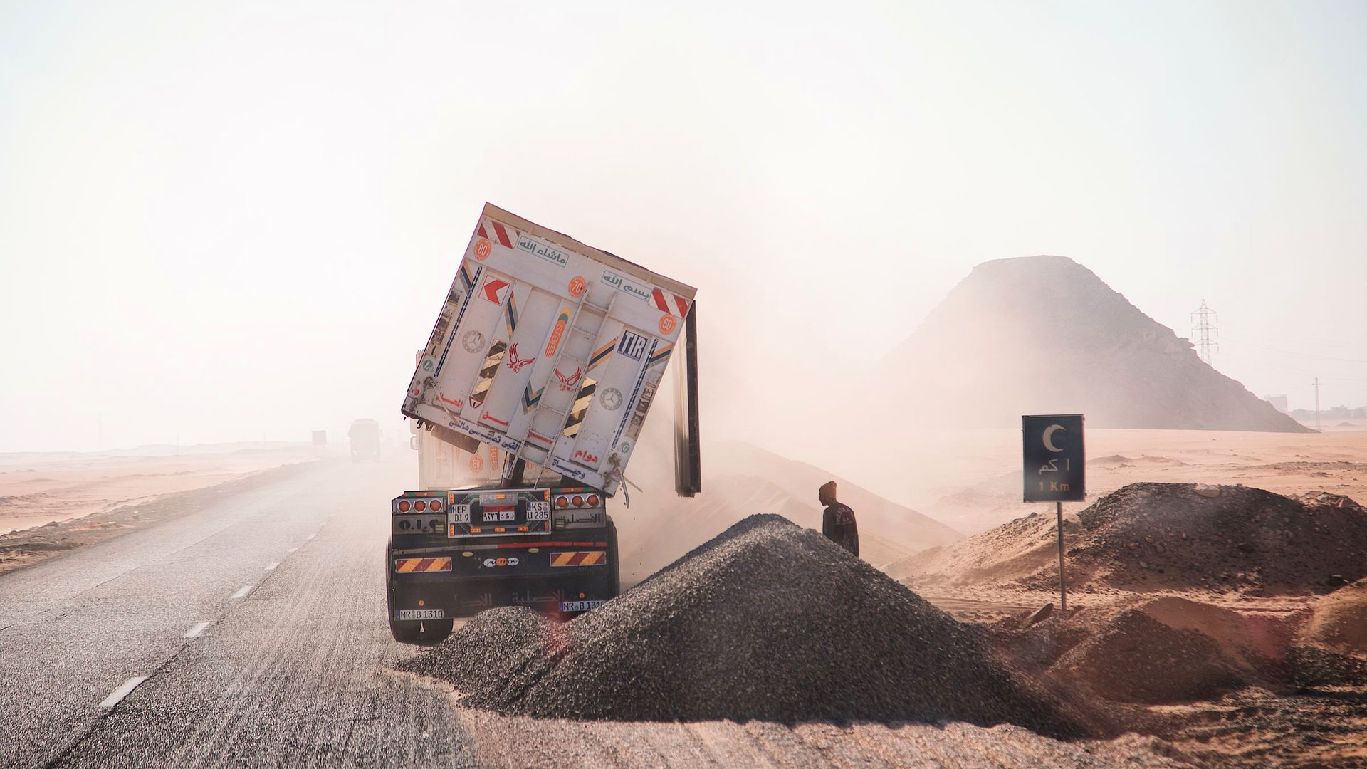 Tipper truck discharging aggregate on a desert road under construction