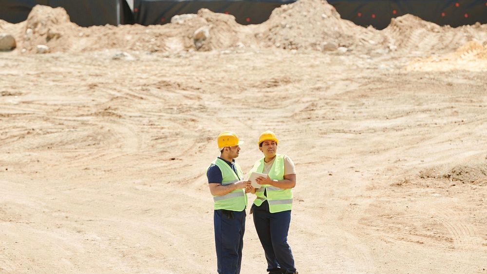 Two site supervisors on a graded sand platform